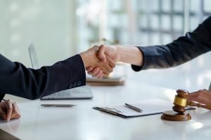 Businessman shaking hands partner lawyers or attorneys discussing a contract agreement.