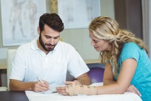 Physiotherapist writing report next to the patient