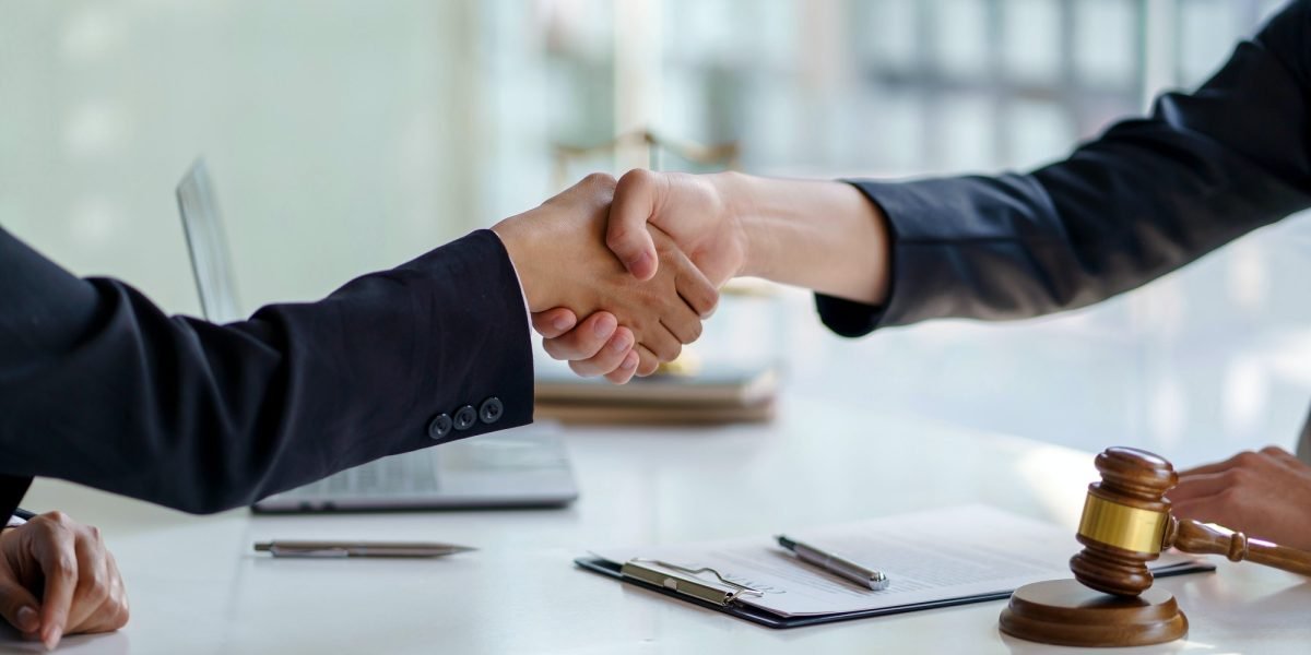 Businessman shaking hands partner lawyers or attorneys discussing a contract agreement.