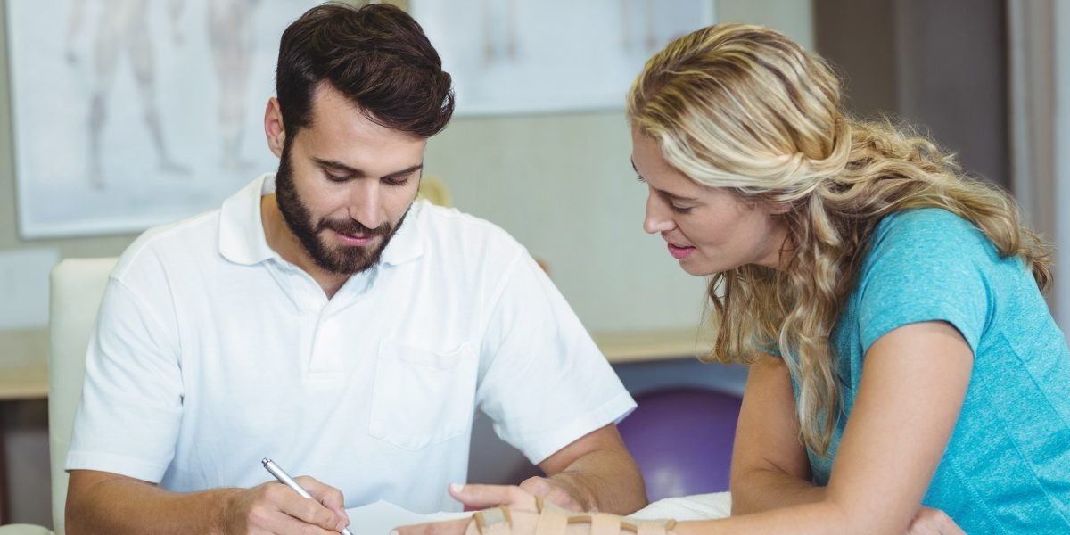 Physiotherapist writing report next to the patient